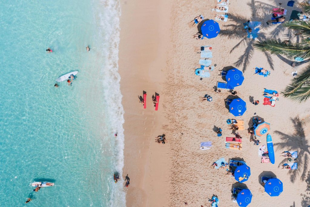 Aerial view of tropical beach with turquoise water and blue umbrellas